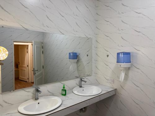 a bathroom with two sinks and a mirror at فيلا الريف in Kusāt