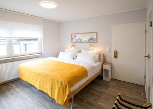 a bedroom with a large bed with a yellow blanket at Hotel Seehof Norderney OHG in Norderney