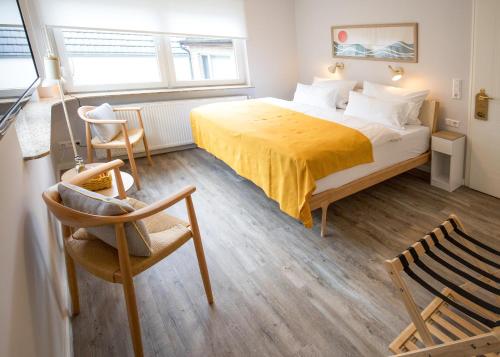 a bedroom with a bed with a yellow blanket and a chair at Hotel Seehof Norderney OHG in Norderney