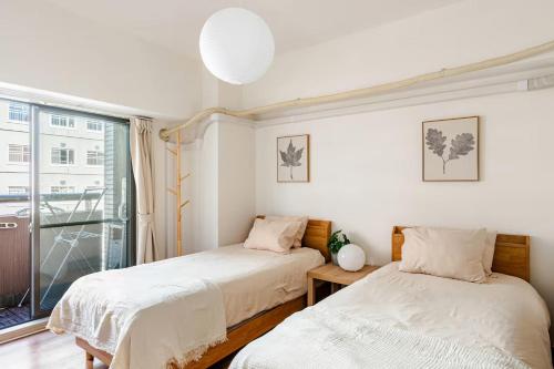 two beds in a room with a window at Cozy Japandi 3LDK in Namba for Groups in Osaka