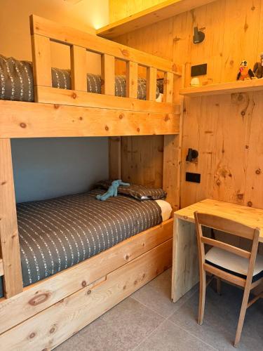 a bedroom with a bunk bed with a desk and a chair at Il Fienile di Ebbe in Bormio