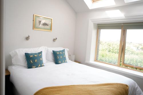 a bedroom with a white bed with blue pillows and a window at Cymyran Terrace in Holyhead