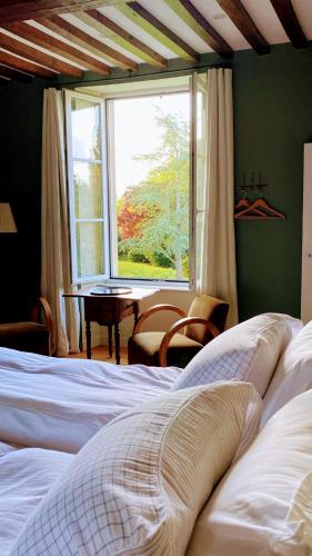 a bedroom with a bed and a window and a table at Les Prés du Manoir in Le Manoir