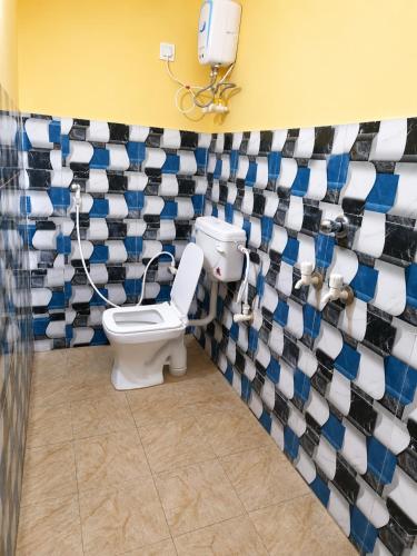 a bathroom with a toilet and a wall with blue and white tiles at Hotel Alankar Lodge Kharagpur in Kharagpur