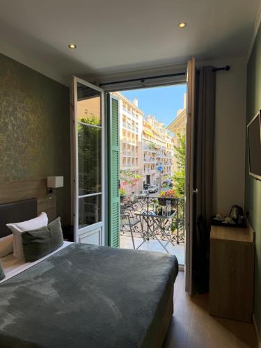 a bedroom with a bed and a sliding glass door at Hôtel Parisien in Nice