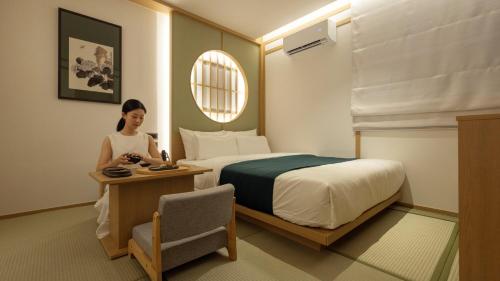 a woman in a hotel room with a bed at Anook Ryokan Hotel Suwon Ingye in Suwon