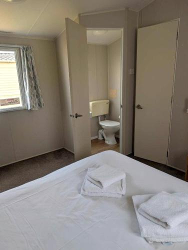 a bedroom with a white bed with two towels on it at Seashell Cove - 2 bedrooms sleeps 6 in Dymchurch