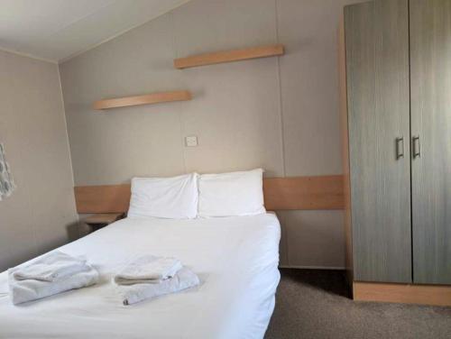 a bedroom with a white bed with towels on it at Seashell Cove - 2 bedrooms sleeps 6 in Dymchurch