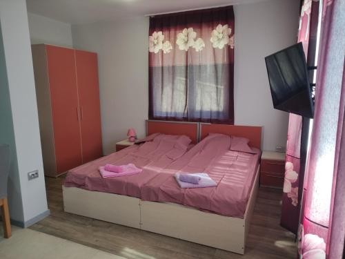 a bedroom with a bed with pink sheets and a flat screen tv at Miranis in Byala