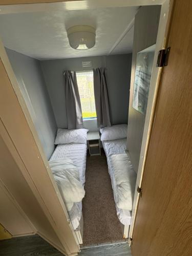 a small room with two beds and a window at 137 sealands, 3 bed, 8 berth caravan hire, ingoldmells, skegness recently modernised in Ingoldmells