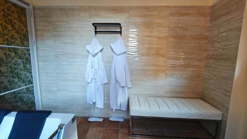 two white robes hanging on a wooden wall at Montefiori Luxury Suite & Spa in Bologna