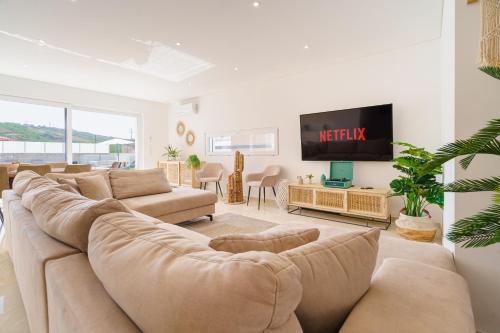 a living room with a large couch and a tv at Paradise Villa Sea - Signature by Paradise Portugal in Ribamar