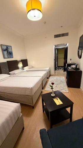 a hotel room with two beds and a table at Saif Al Majd Hotel in Mecca