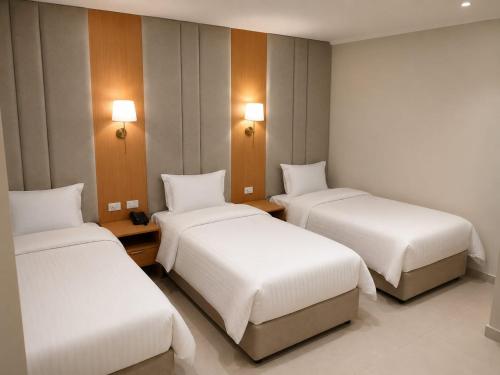 three beds in a room with white sheets at Up Town Crown Hotel in Cairo
