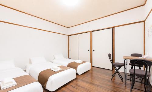 a hotel room with three beds and a desk at Kasuga Good Place House in Kasugabaru