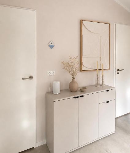 a white room with a mirror and a white cabinet at Huisje Mae in Nunspeet