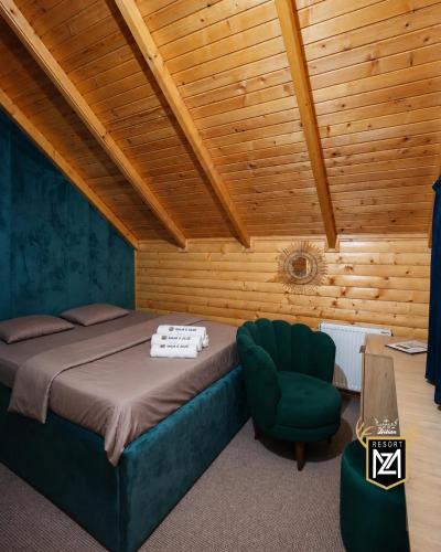a bedroom with a bed and a green chair at Resort Maja e Zezë in Gnjilane