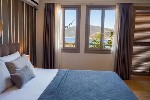 a bedroom with a bed and two windows at Kalkan Ayapa Hotel in Kaş