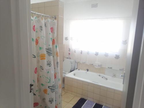 a bathroom with a tub and a toilet and a shower curtain at Royal Oasis in Mahikeng