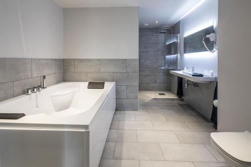 a white bathroom with a tub and a toilet at Thon Hotel Victoria Hamar in Hamar