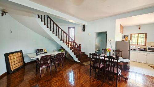 a kitchen and dining room with a dining table and a staircase at La Parshwa Villa Maré in Mahabalipuram