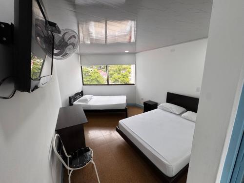 a small bedroom with two beds and a window at Hotel La Popa Honda Tolima in Honda