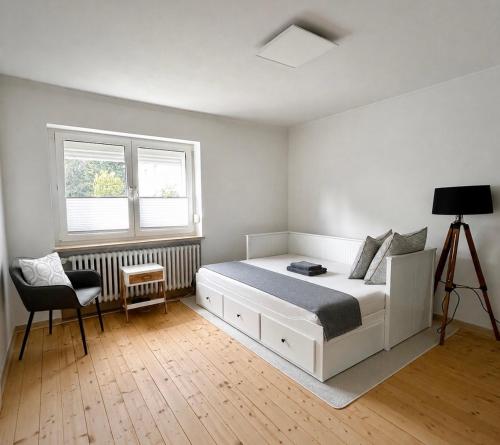 a bedroom with a bed and a chair and two windows at Rebenlaub in Heringen