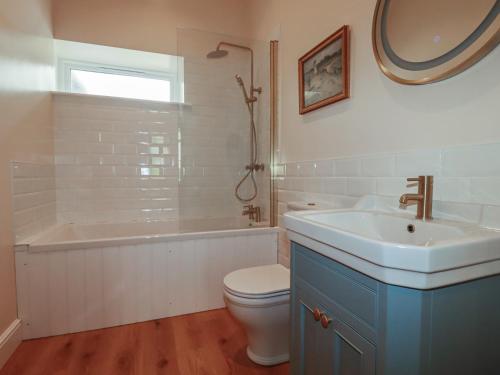 a bathroom with a sink and a tub and a toilet at Farthings, The Old Chapel in St Austell