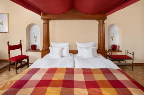 a bedroom with two beds and two red chairs at Burg & Gästehaus by Schwarzenstein in Geisenheim