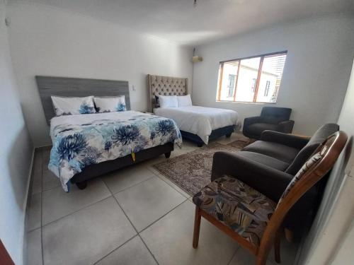 a bedroom with two beds and a chair and a couch at Sintha guest house in Kraaifontein
