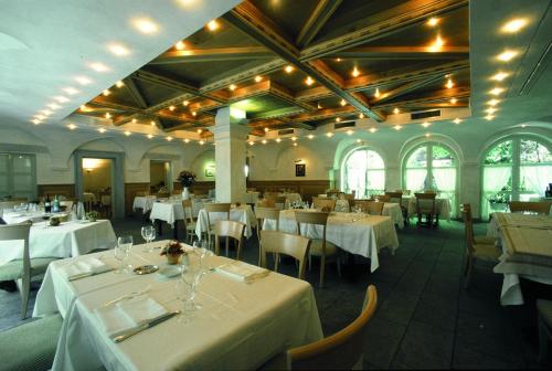 una sala da pranzo con tavoli e sedie bianchi di Hotel Margna a Morbegno