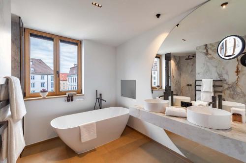 a bathroom with three sinks and a large tub at Hotel Maximilian’s in Augsburg