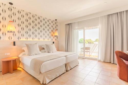 a bedroom with a large white bed and a window at Hotel Cala Dor - Adults Only in Cala d´Or
