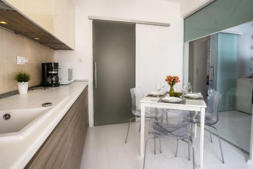 a kitchen with a white table and chairs and a sink at Summerland Nikos Residence in Mamaia