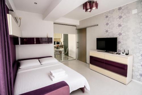 a bedroom with a bed and a flat screen tv at Summerland Nikos Residence in Mamaia