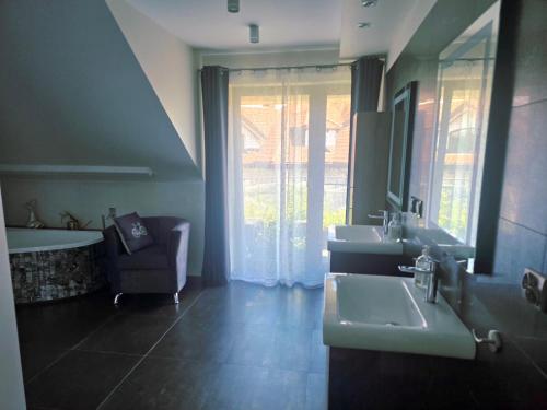 a bathroom with two sinks and a tub and a mirror at Szary odpoczynek na piętrze - wieś Pogórze, dla zmotoryzowanych in Pogórze