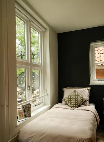 a bedroom with a bed and two windows at B&B Bistro Lochem in Lochem