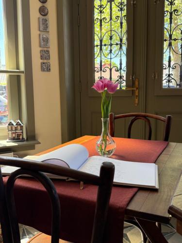 a table with a vase of flowers and a book at BnB 't Ambacht - Boutique Hotel in Hendrik-Ido-Ambacht