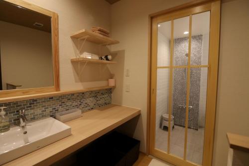 a bathroom with a sink and a shower with a mirror at Yanagawa B&B hatago in Yanagawa