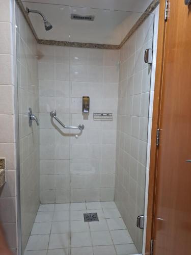 a bathroom with a shower with white tiles at Comfort Hotel Taguatinga, Metrô 600m, Sauna piscina academia e garagem Camas king e solteiro in Taguatinga