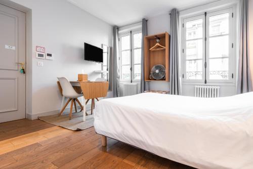 a white bedroom with a bed and a table at Apparts de l'Oncle Louis in Versailles