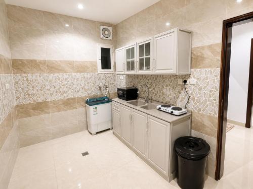 a small kitchen with white cabinets and a trash can at أرياف سويت in Al Baha
