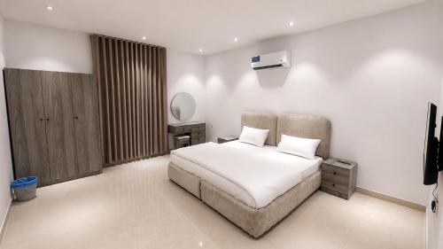 a white bedroom with a bed and a mirror at أرياف سويت in Al Baha