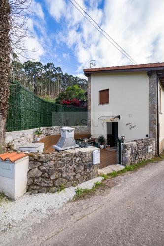 a house with a stone wall next to a street at Atardecer en Gulpiyuri By Silastur in Naves