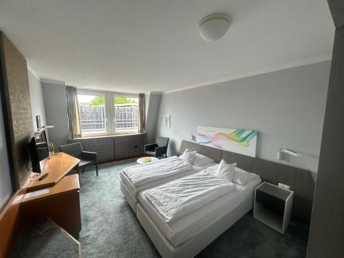 a bedroom with a bed and a desk and a window at Hotel Lachnerhof in Erlangen