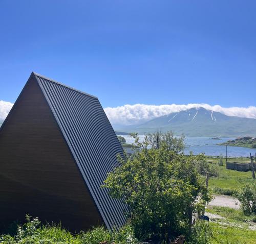 a house with a roof with a mountain in the background at Aurora Cottage Tabatskuri Lake in Tabatsquri