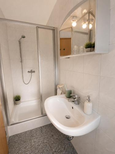 a white bathroom with a sink and a shower at Messeappartementhaus Bockenem direkt an der A7 in Bockenem