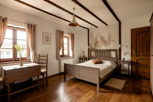 a bedroom with a bed and a desk and windows at Gospodarstwo nad jeziorem in Załom