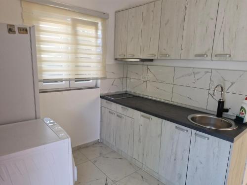 a kitchen with white cabinets and a sink and a refrigerator at Apartman UNA in Bjelila