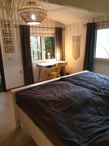 a bedroom with a bed and a desk and windows at Chalet Ritz Ferienhaus in Dieblich